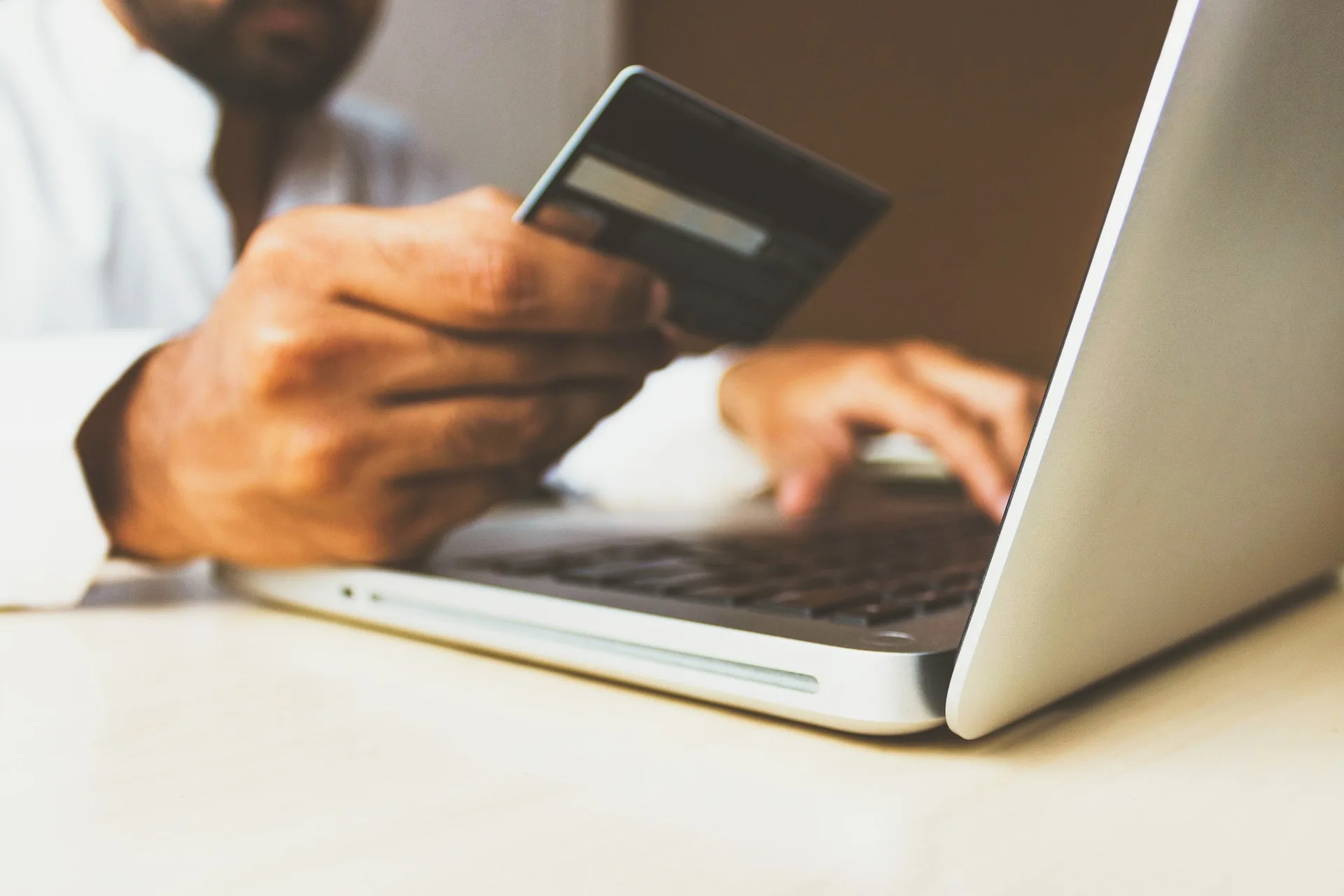 Person is using a secured credit card to make an online purchase on a laptop.