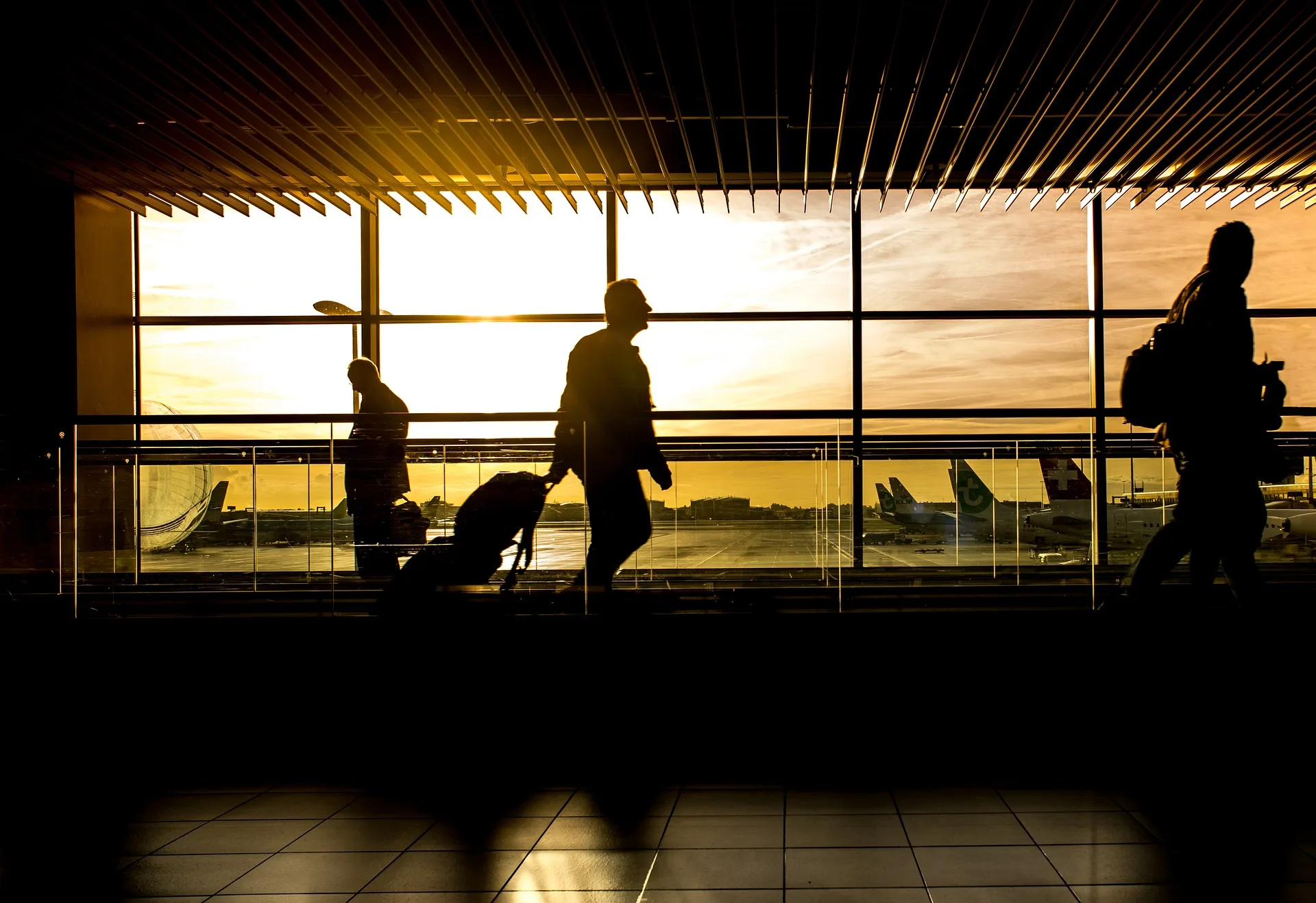 People walking in an airport preparing to travel using a credit card with travel rewards