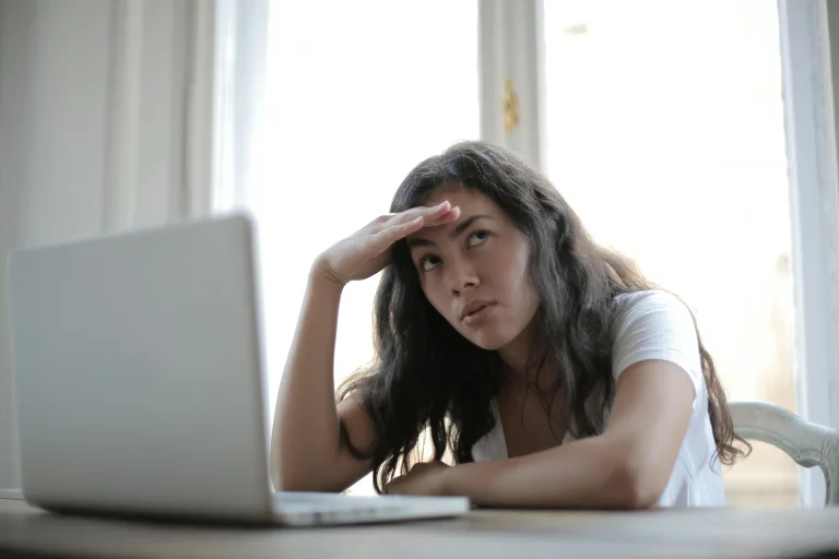 Woman is confused in front of her laptop because of bank account fees.