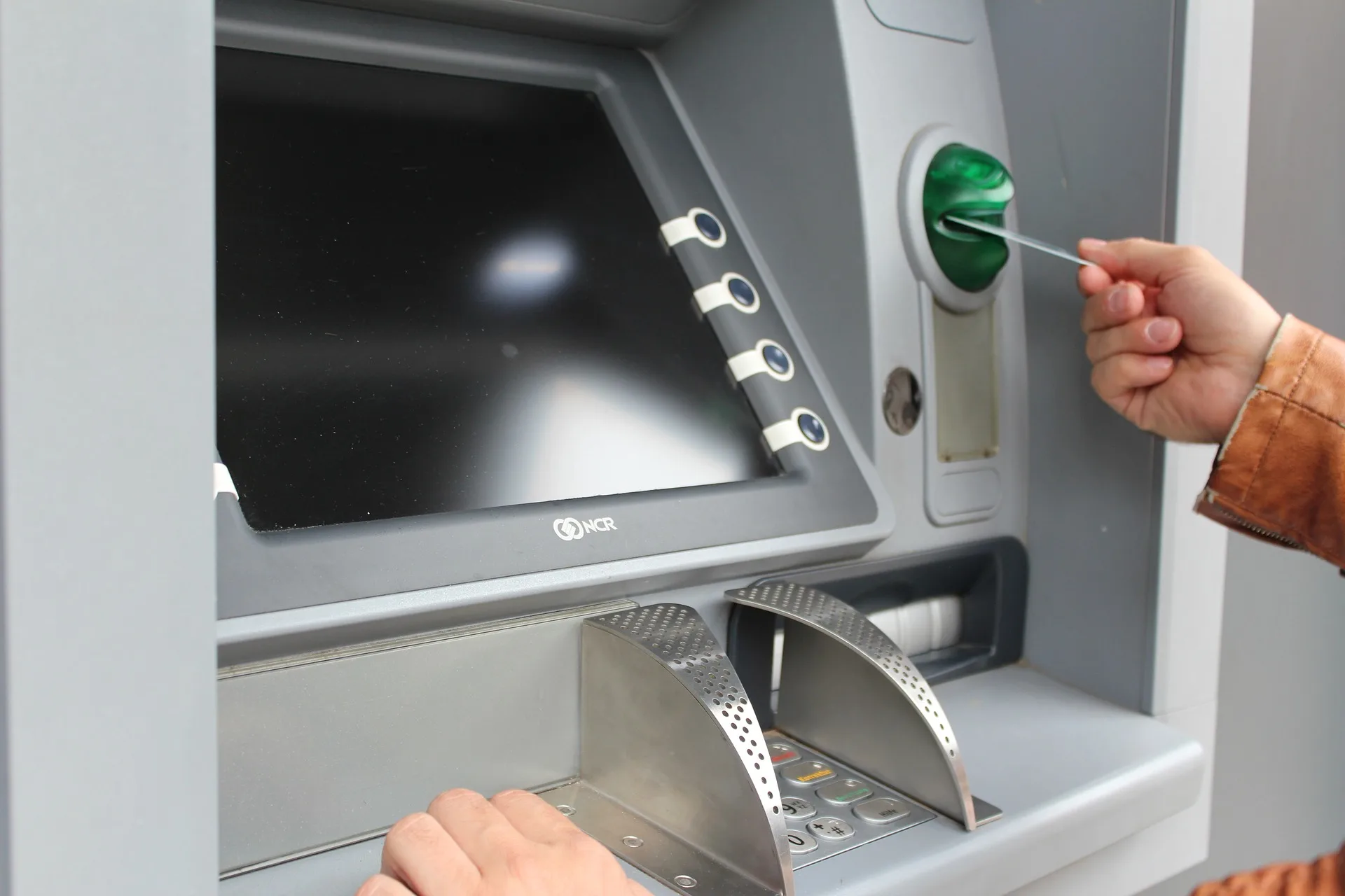 A person uses an ATM to access their chequing or savings account.