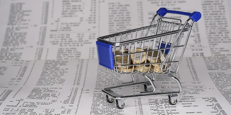 Coins on a shopping cart on top of multiple receipts, to illustrate debt.