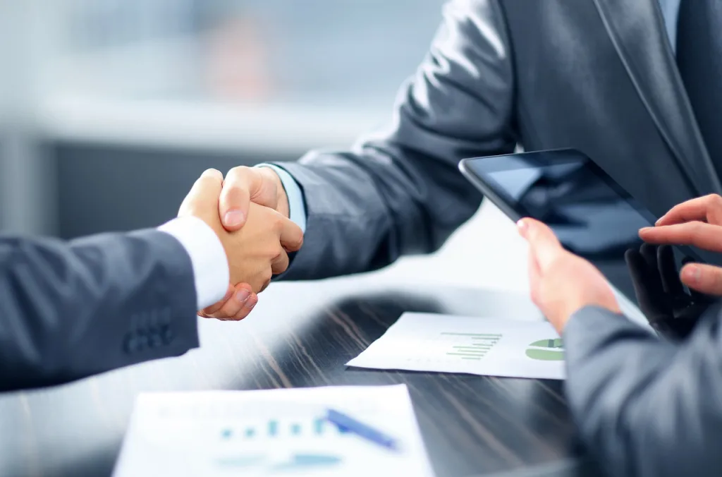 Man shakes hand with bank representative after getting a loan or line of credit approved.