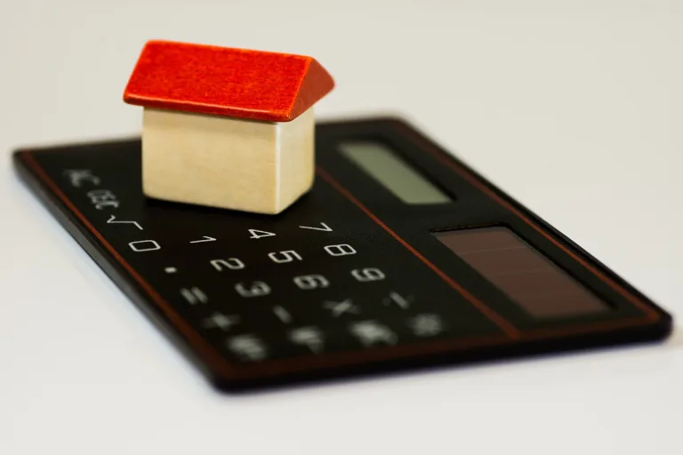 A wooden house on top of a calculator