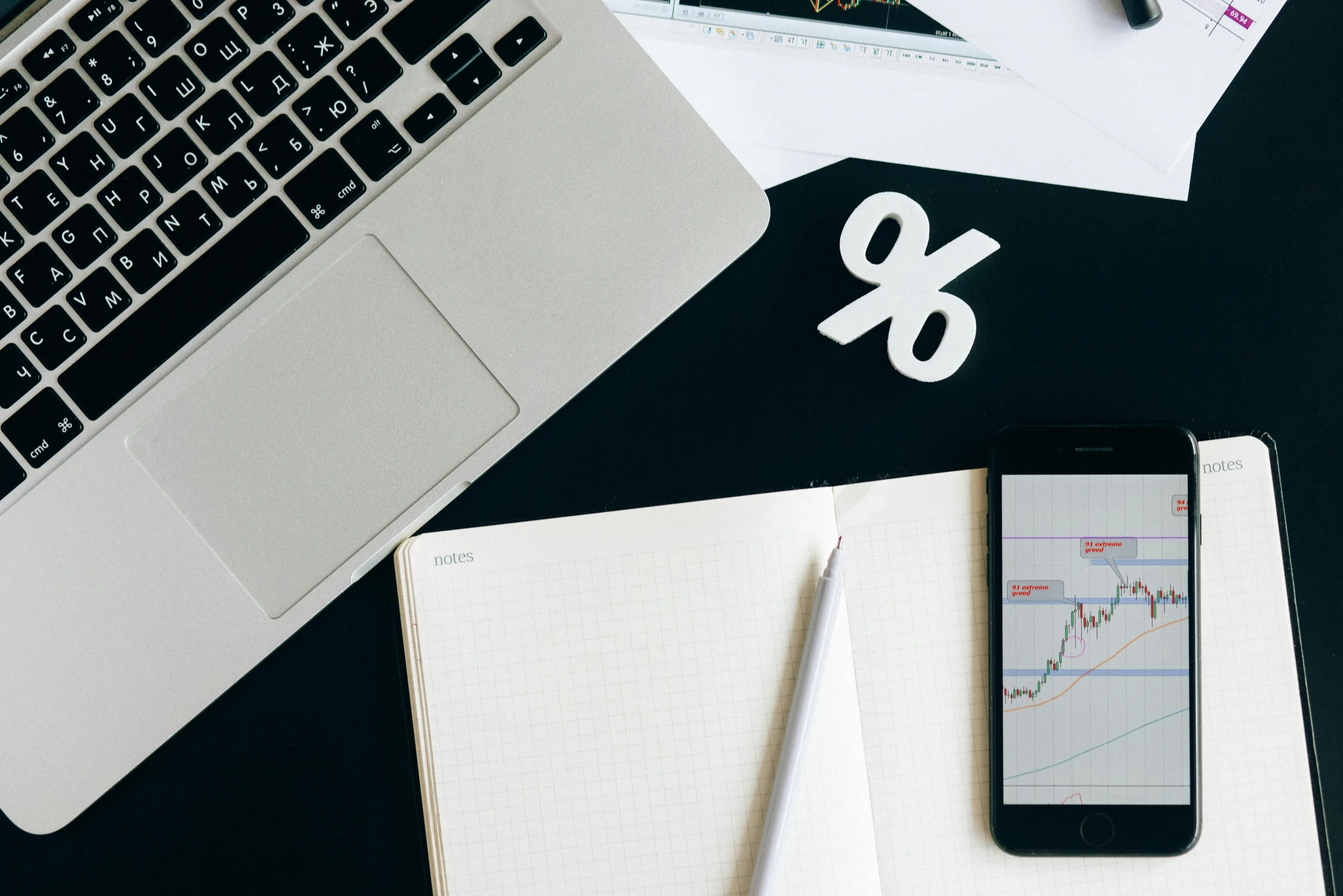 A laptop next to a smartphone with an investment graph on the screen.