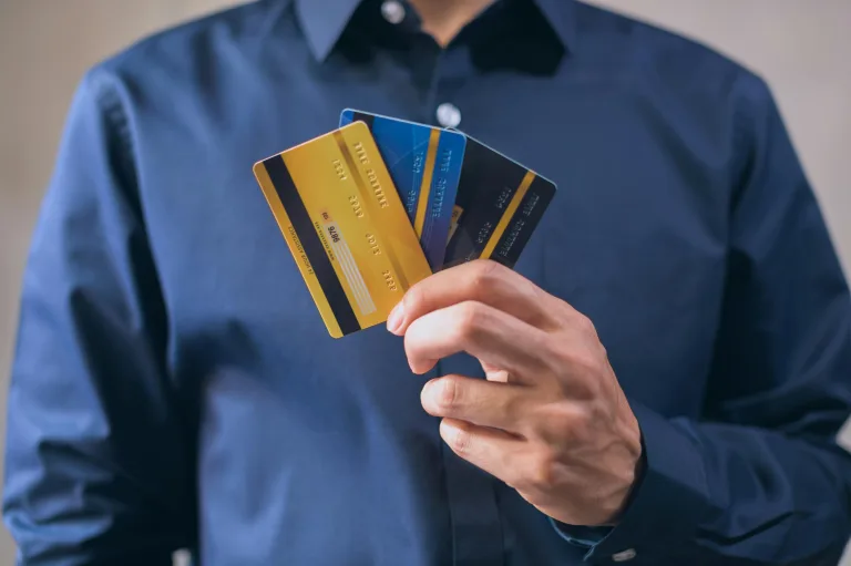 Man holding three different banking cards, to represent multiple bank accounts.