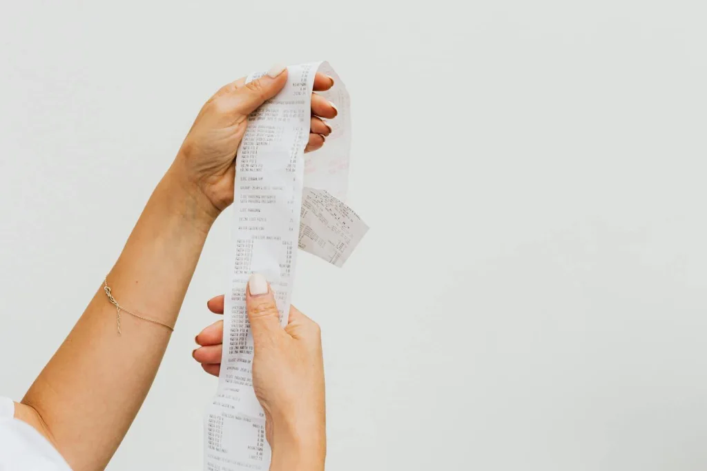 A person is holding a receipt printed on paper, displaying details of a recent transaction.