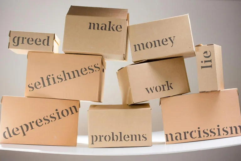 A stack of cardboard boxes featuring various words printed on their surfaces, arranged in a disorganized manner.